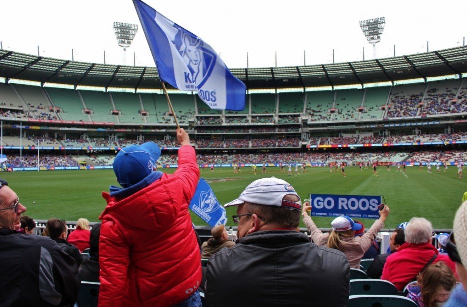 A young fan waves a flag in support of the North Melbourne Kangaroos at an Australian Football match at the MCG