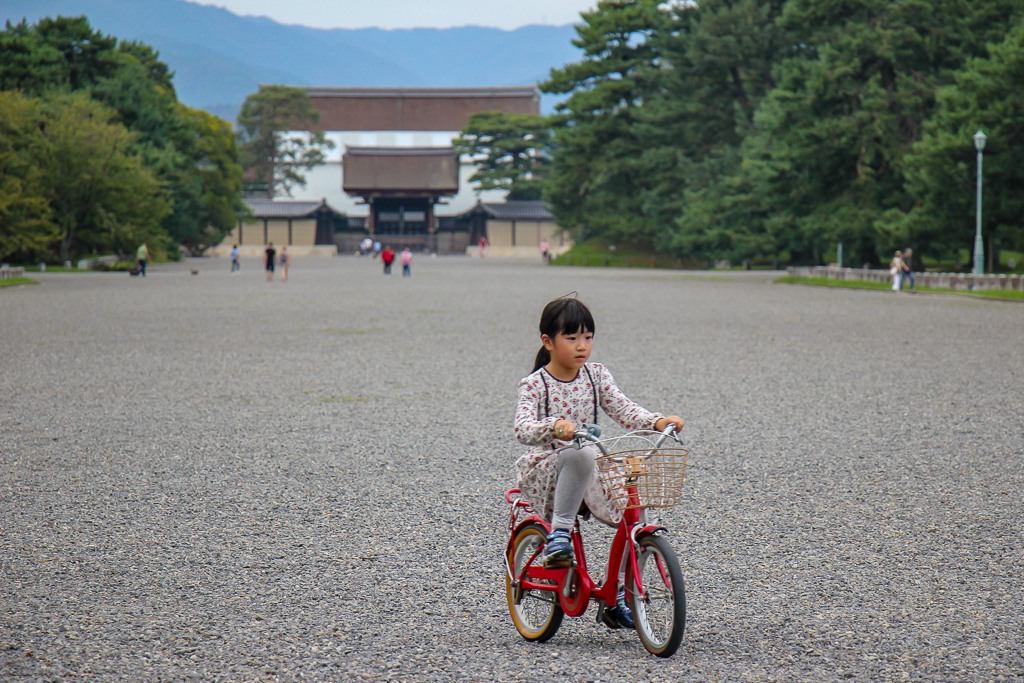 Girl rides bike at Kyoto Imperial Palace in Kyoto, Japan